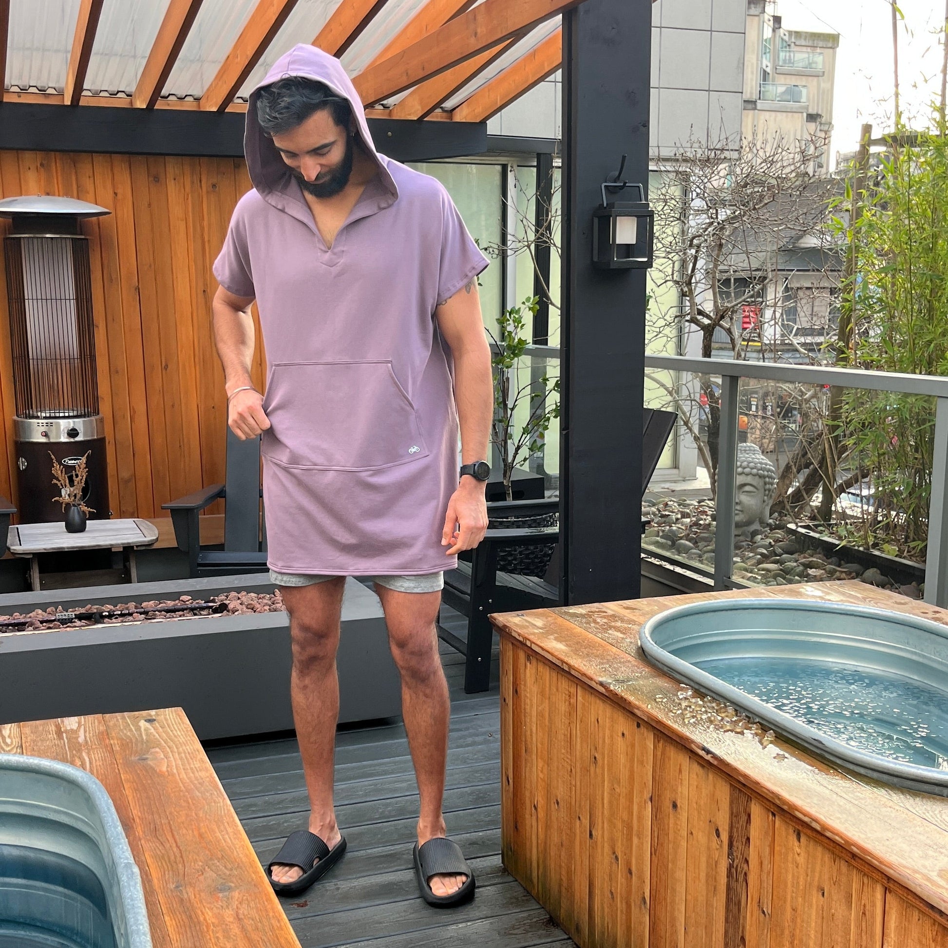 Person in a purple shirt and shorts standing on a wooden deck with outdoor furniture.