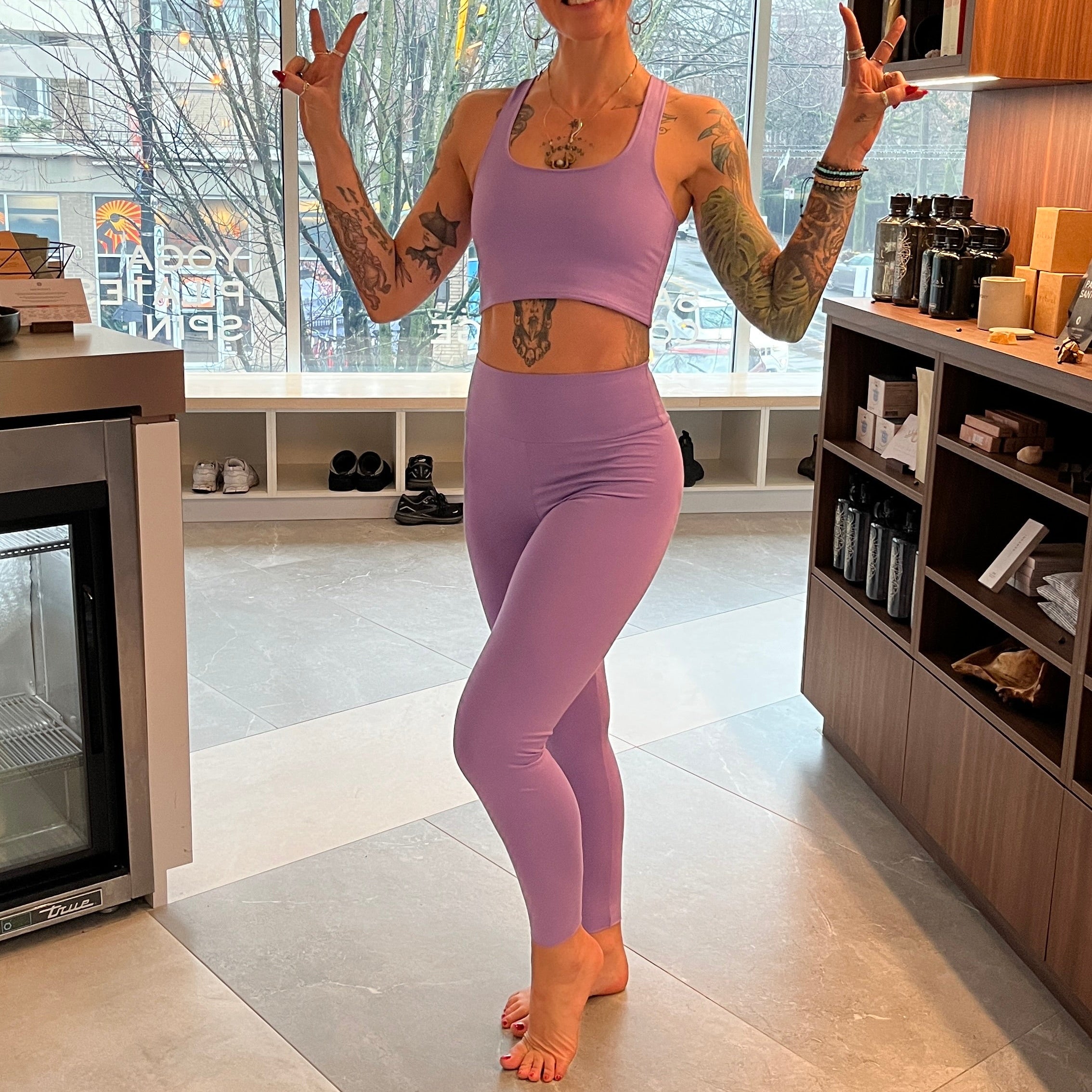 Person in purple athletic wear posing in a modern yoga studio reception

