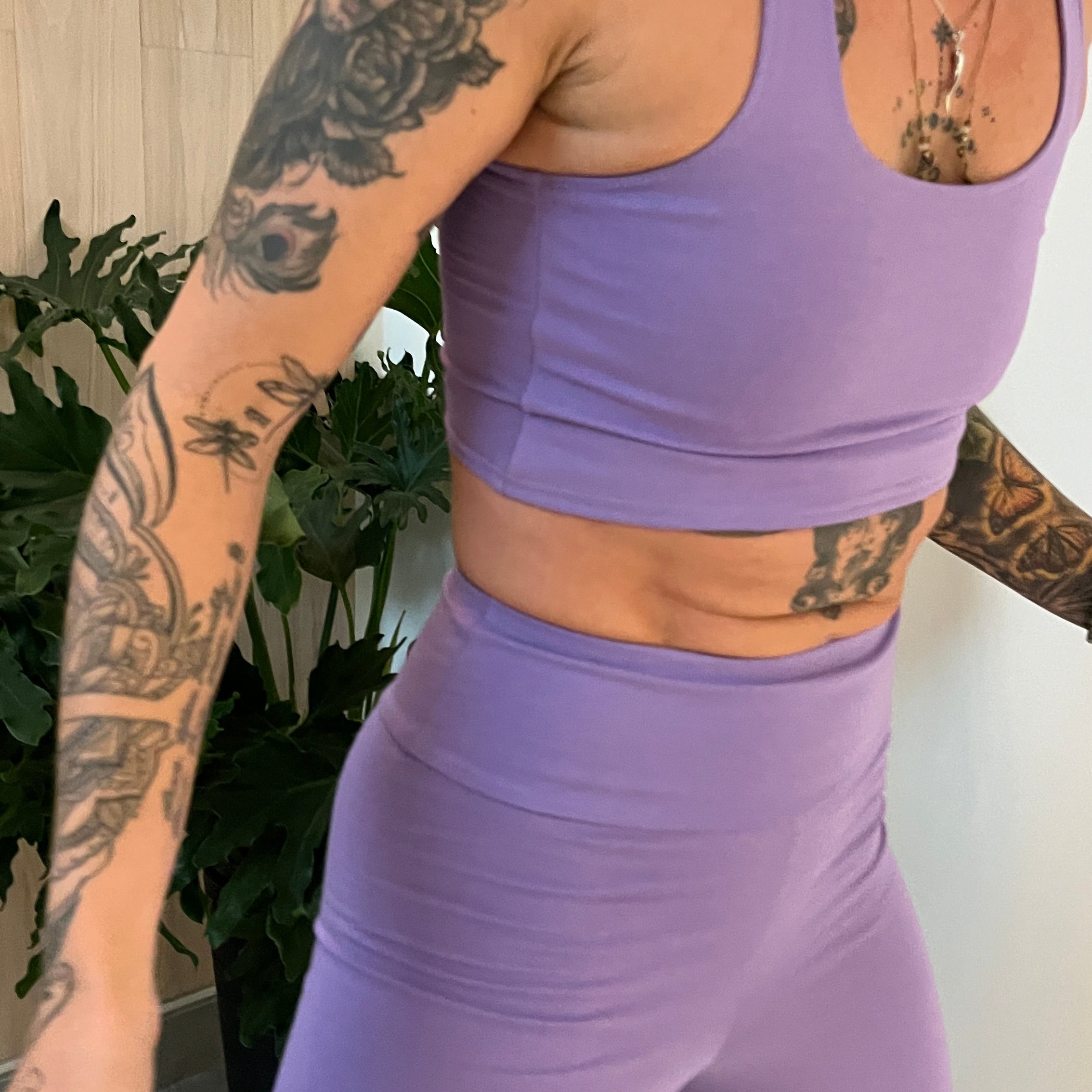 Person wearing a purple athletic outfit with tattoos visible on arms and neck.