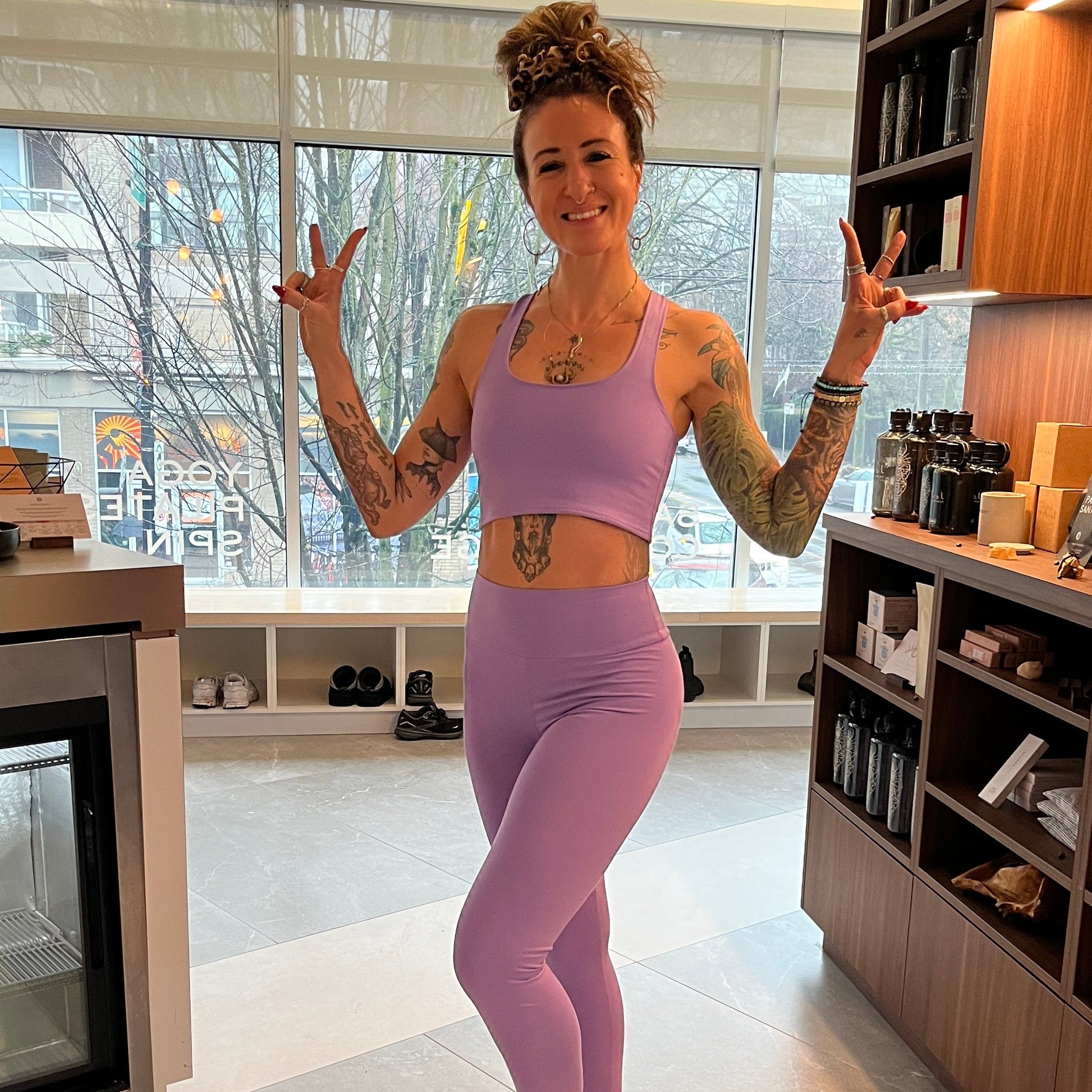 Person in purple athletic wear posing in a modern yoga studio reception area


