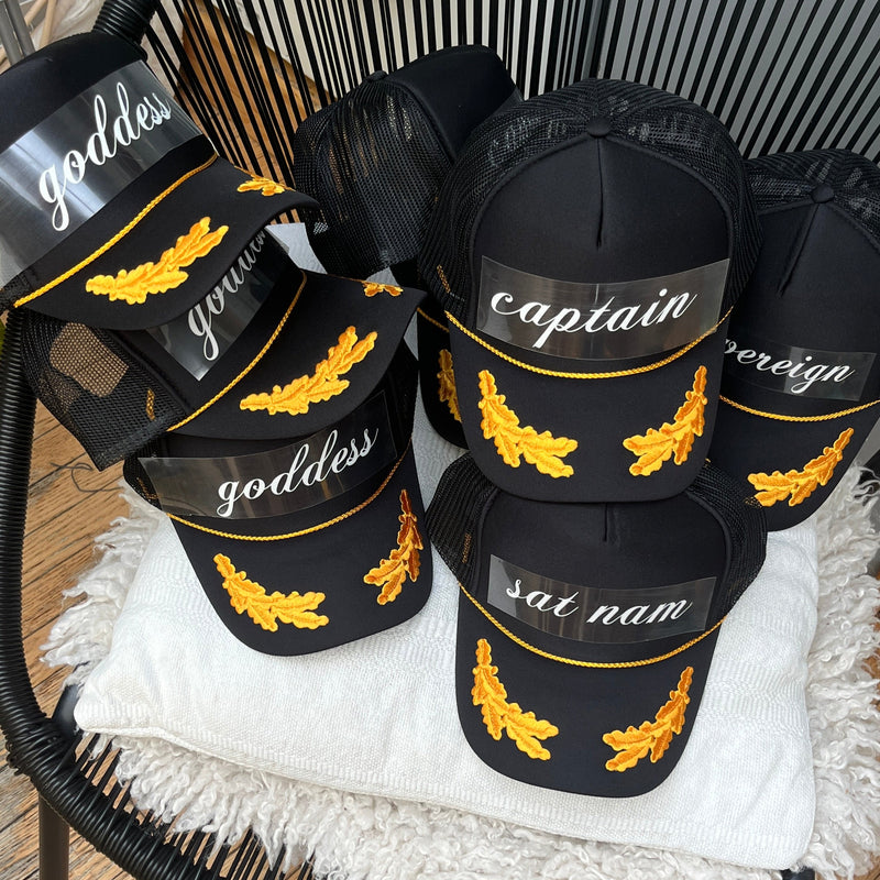 Black hats with gold embroidery on a black chair with white cushion