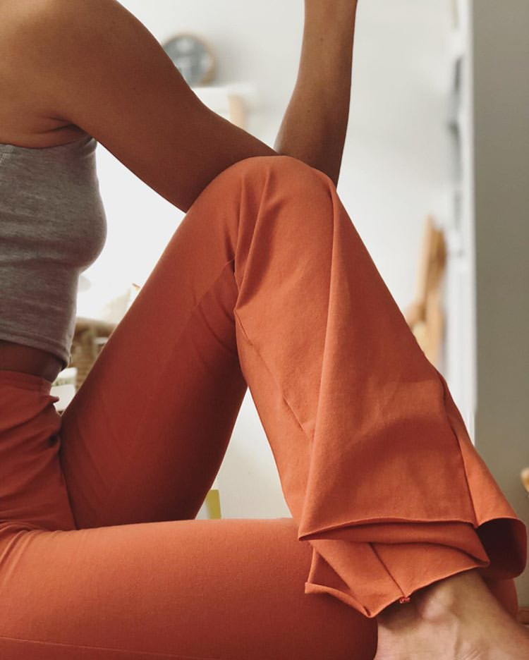 Person wearing orange pants sitting on a couch with a blurred background