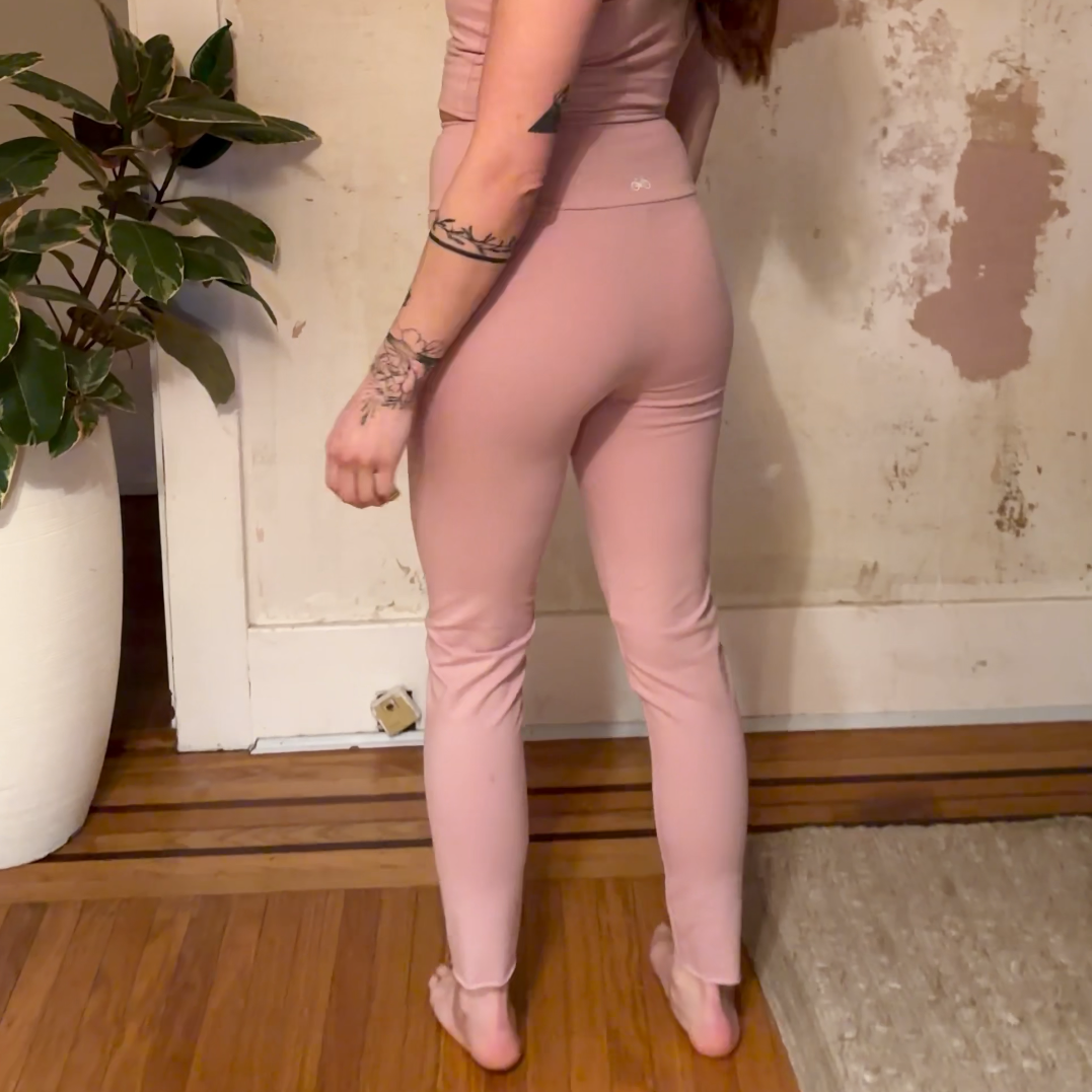 Woman in a pink outfit standing in a boho living room with deconstructed wallpaper.