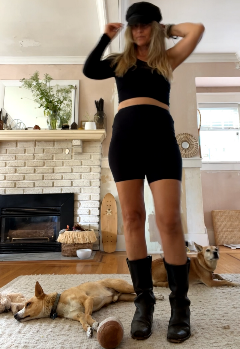 Person in black outfit with a dog lying on the floor in a living room.