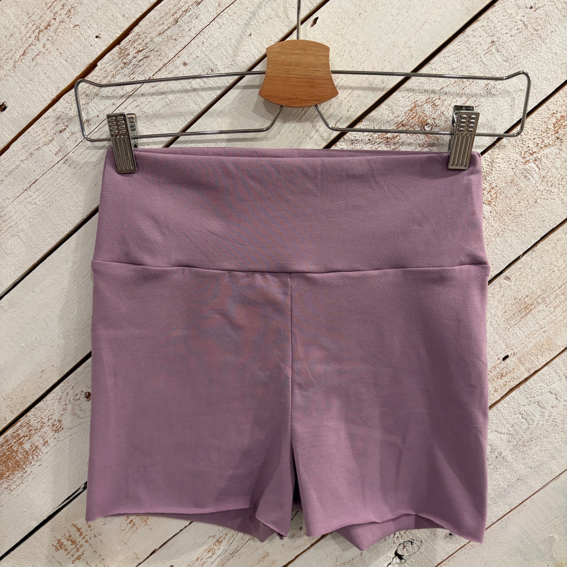 purple short shorts hanging on a wooden white-washed barn door
