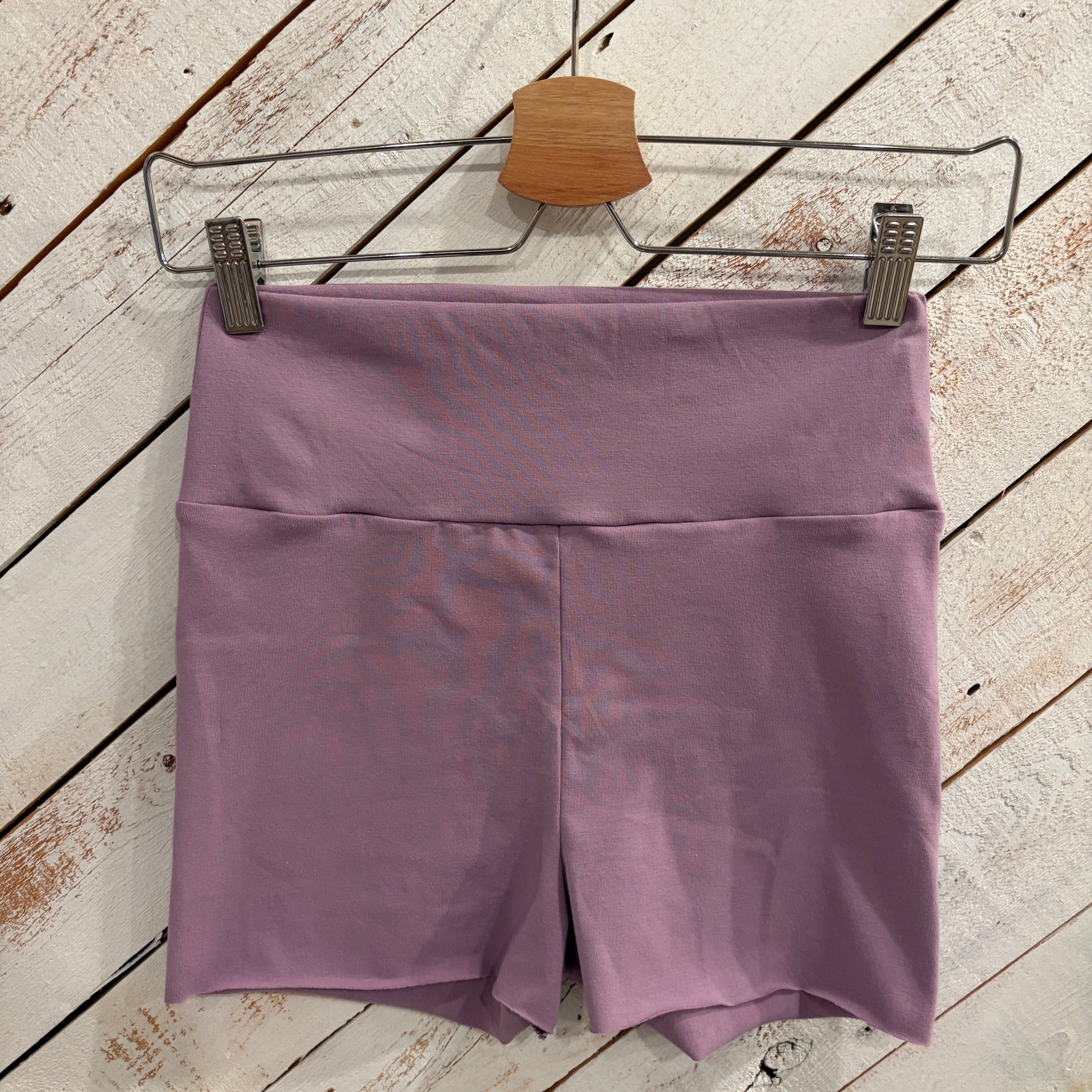 purple short shorts hanging on a wooden white-washed barn door
