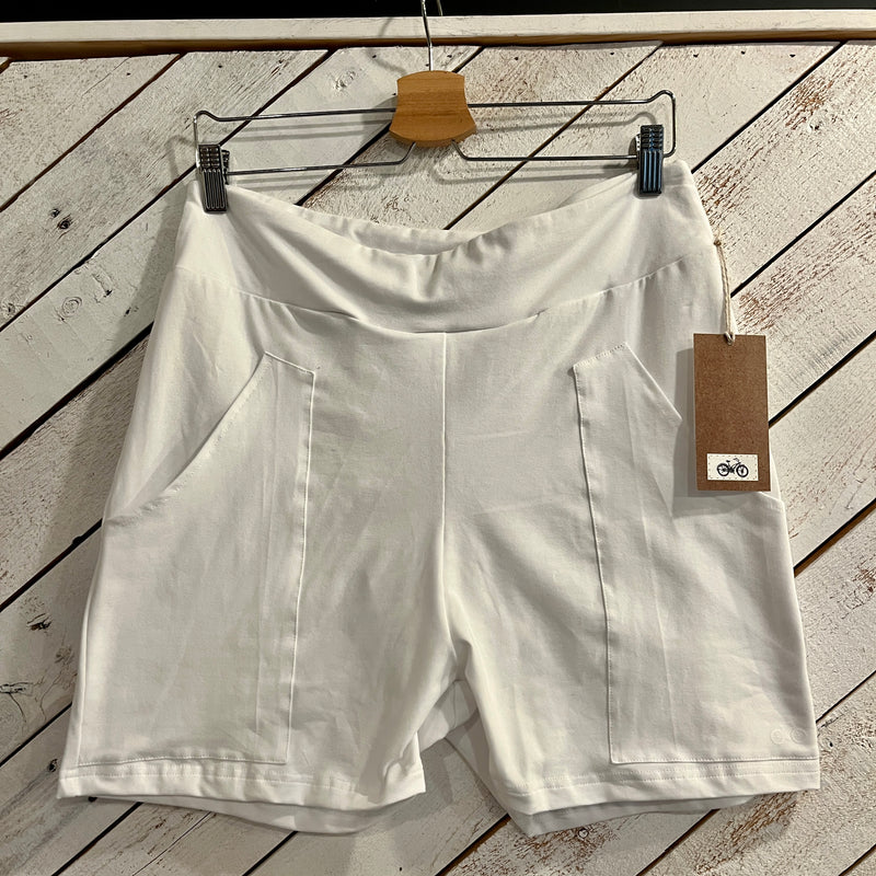 White shorts hanging on a wooden surface with a bicycle 
tag attached.