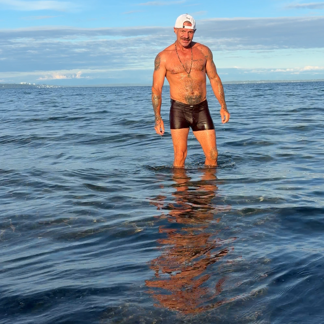 Man standing in the ocean with a clear blue sky above