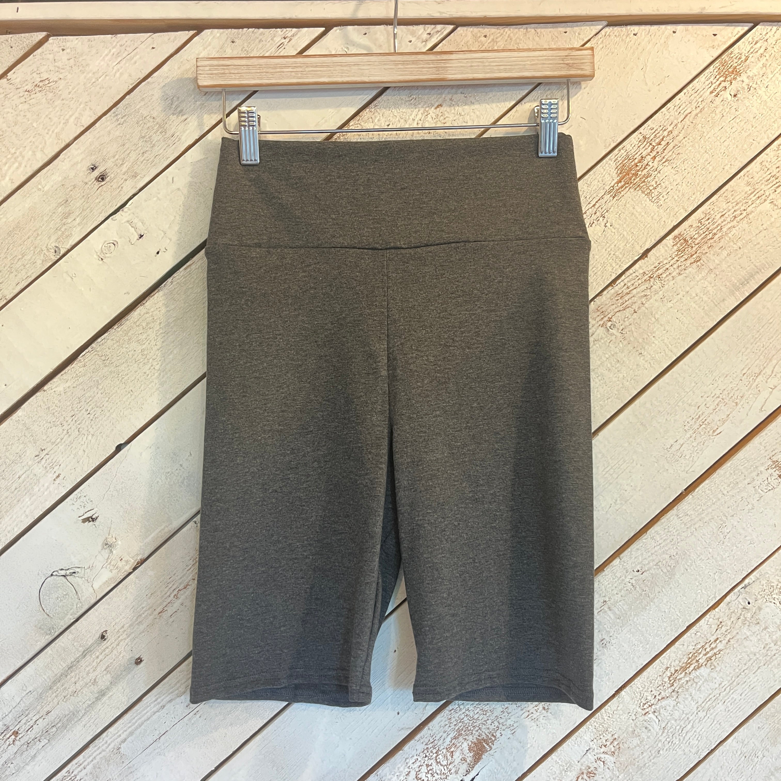 Grey bike shorts hanging on a wooden hanger against a wooden background
