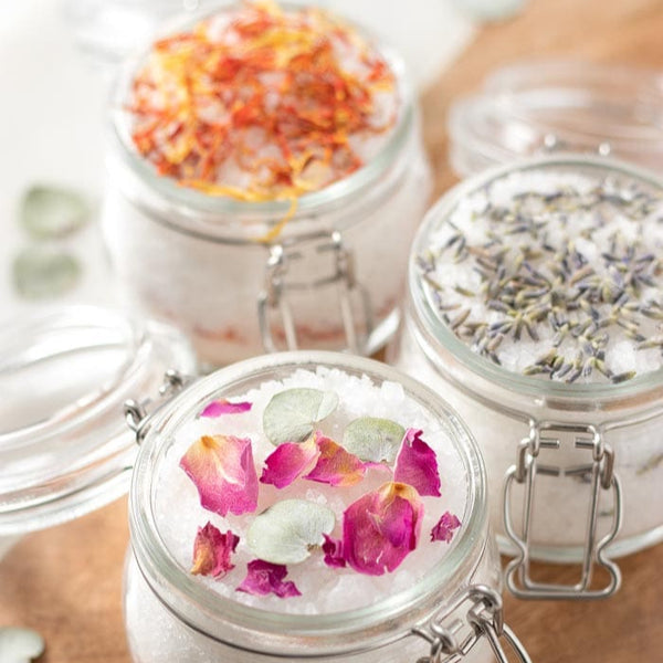 Glass jars with floral petal toppings on a bath salts