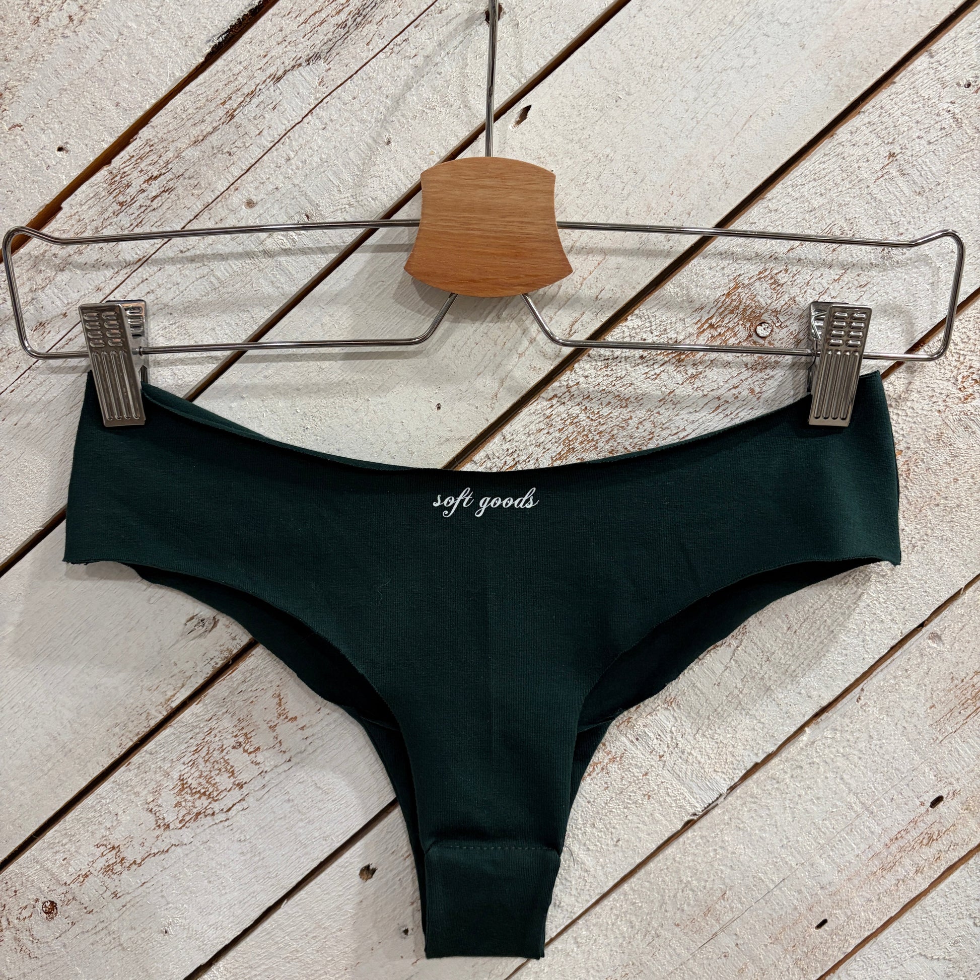 dark green swimsuit bottom on a wooden surface with a hanger.