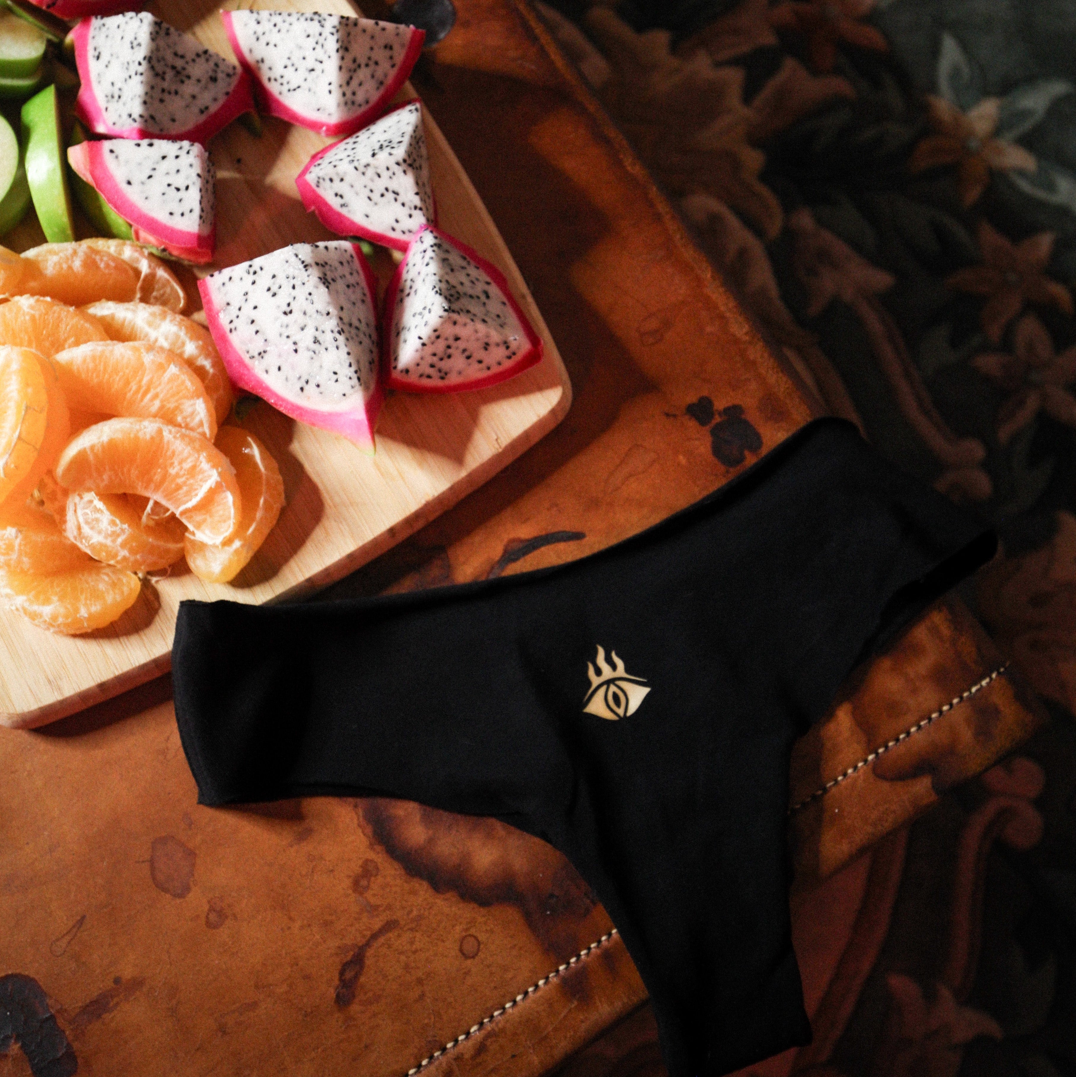 Dragon fruit slices on a wooden board with black underwear on a textured surface