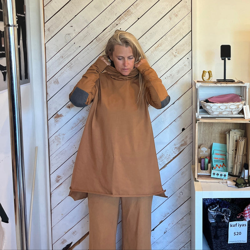 Person in a brown outfit standing in a room with wooden sliding door and shelves.